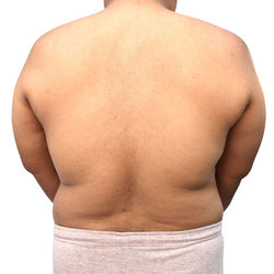 Midsection of shirtless man standing against white background