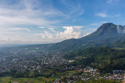 Aerial view of townscape and mountains against sky