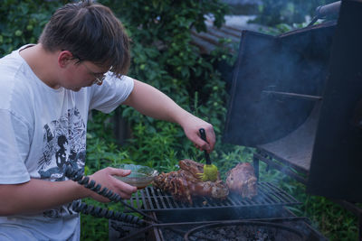 A high-angle view of a boy cooking on an open fire. the concept of a weekend. meat on the fire