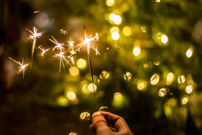 Cropped hand of woman holding sparkler