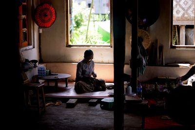 Rear view of man sitting on table at home