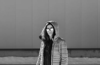 Portrait of woman wearing sunglasses and hooded jacket during winter