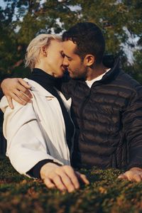 Couple kissing while standing in park against trees