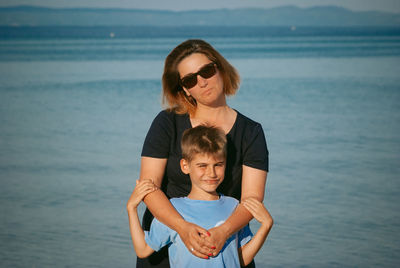 Portrait of woman with son standing at beach