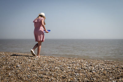 Girl playing at beach against clear sky