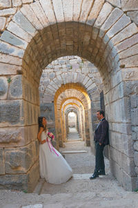 Side view of a woman standing against stone wall