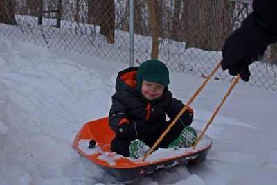 Boy sitting on toboggan pulled by his father