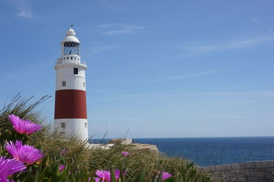 Lighthouse by sea against sky