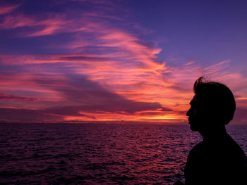 Silhouette woman looking at sea against sky during sunset