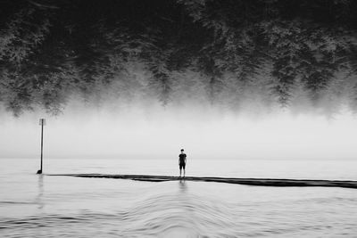 Silhouette man standing by sea against sky