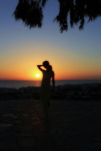 Silhouette of man standing by sea at sunset