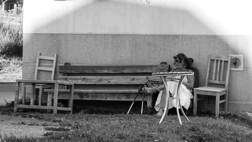 Woman sitting on chair by bench