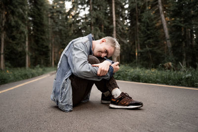 Young man sitting on road in forest