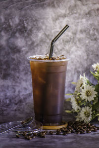 Thai coffee in a tall plastic cup there is steam next to the glass, cold.