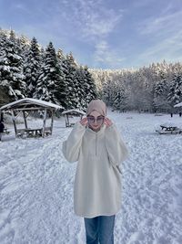 Portrait of young woman standing on snow covered field