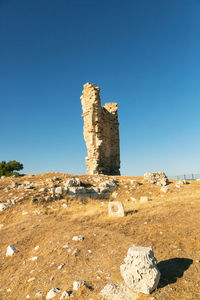 Cross on rock against clear blue sky