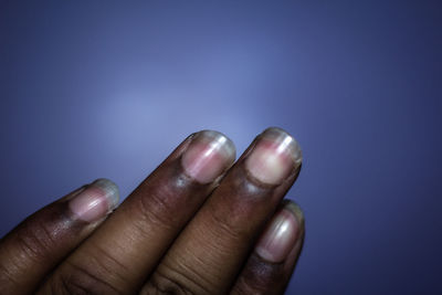 Close-up of human hand against blue background