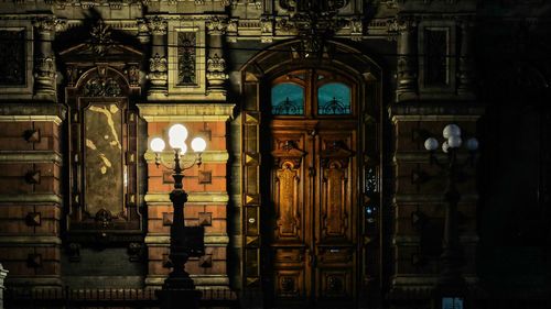 Illuminated antique street light against building at night