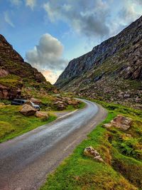 Road leading towards mountains against sky