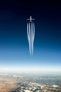 Low angle view of airplane with trail in flight