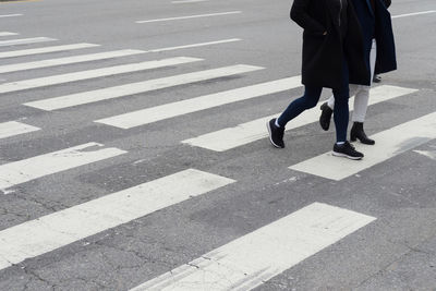 Low section of woman walking on zebra crossing