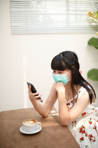 Woman using mobile phone while sitting on table