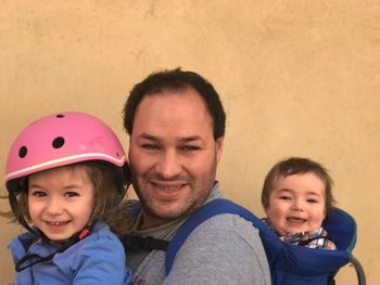 Portrait of man with children against wall