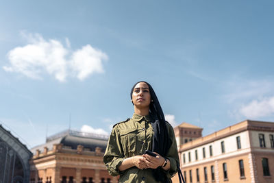 Young woman standing against sky