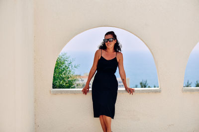 Full length portrait of woman standing against wall