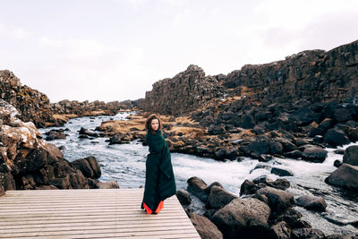 Woman standing on rock against sky