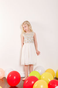 Full length of girl standing by wall at home