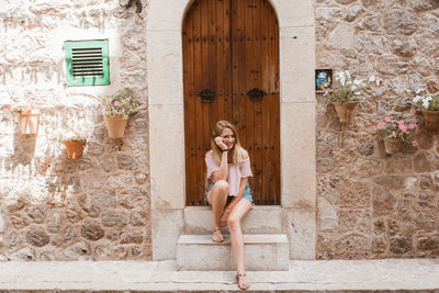 Smiling blonde woman sitting and waiting in the entrance with a door