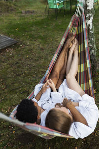 Young couple in bathrobes relaxing in hammock