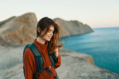 Young woman looking at sea shore against sky