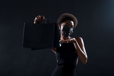 Young woman holding umbrella against black background