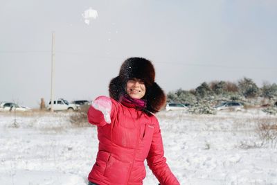 Beautiful woman standing on field against sky during winter