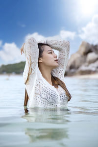 Woman with reflection in water against sky