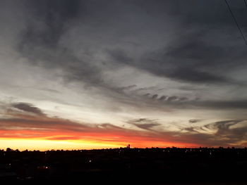 Silhouette landscape against dramatic sky during sunset