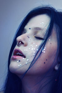 Close-up of young woman with star shape glitters on face