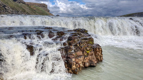 Scenic view of waterfall against sky