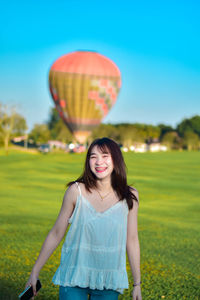 Portrait of young woman with balloons against sky