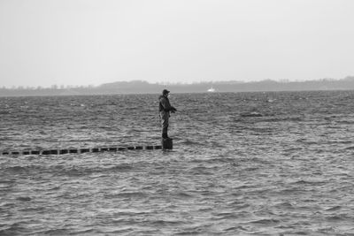 Man surfing on sea against clear sky