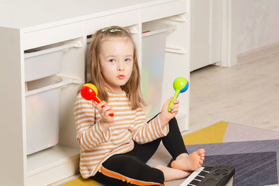 Child playing maracas at home. child portrait looking to the side