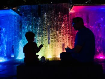 Silhouette people sitting in aquarium