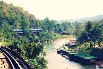 Boats on river amidst trees against clear sky