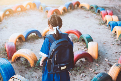 Rear view of girl wearing backpack while standing amidst multi colored tires