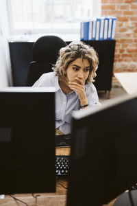 Female professional looking at computer while sitting at desk in office