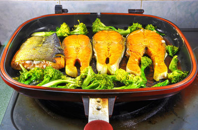 High angle view of salmon and broccoli in pan on stove