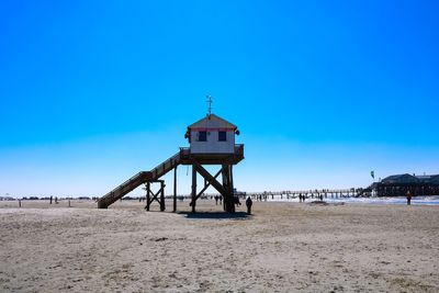 Lifeguard hut on beach against blue sky