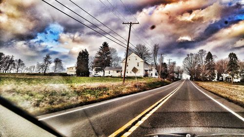 Road passing through landscape against cloudy sky